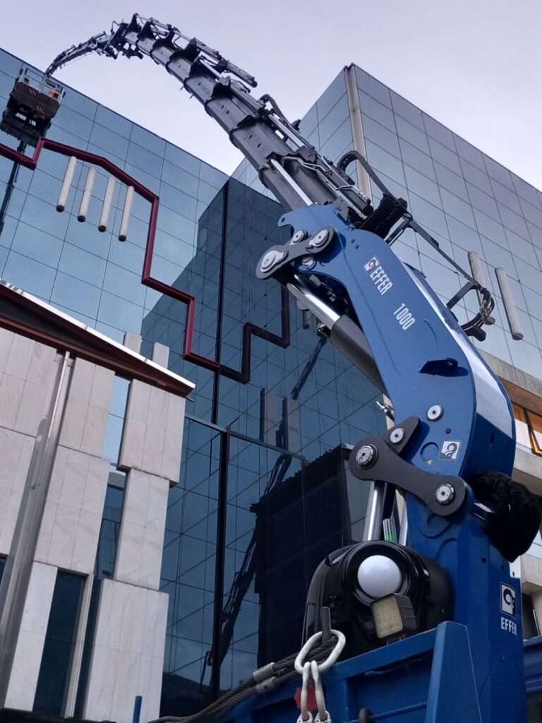 Γερανοφόρο όχημα EFFER 1000 σε πλήρη έκταση μπροστά από κτίριο με καθρέπτες - Βρεττός Γερανοί